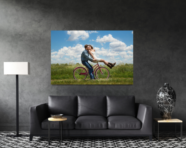 גבר מרכיב אישה על אופניים, רקע דשא ושמיים מעוננים, תמונה פסטורלית של חופש ורומנטיקה.