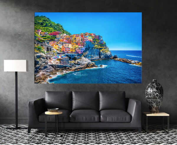 תמונה של בתים צבעוניים בחצי האי האיטלקי עם שמיים וים כחולים, תלויה בסלון כהה, יוצרת ניגודיות מרהיבה עם צבעים חיים.