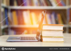 תמונה של מחשב נייד פתוח נשען על ספרים ברקע של ספריה_37882680