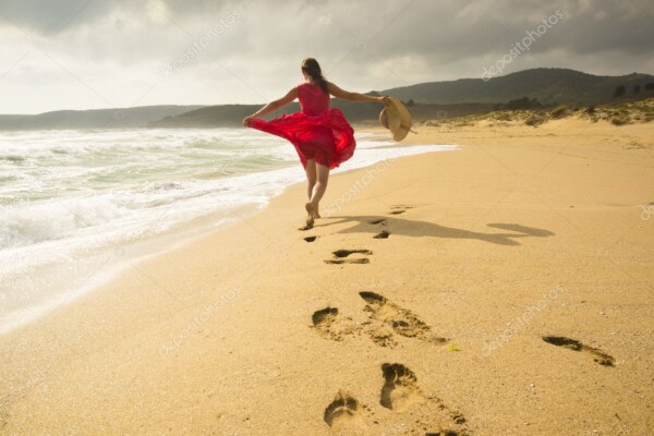 אישה רצה על החוף - עם שמלה אדומה - 14069831
