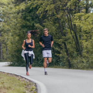 גבר ואישה רצים בדרך אספלט בתוך יער - תמונת טבע - תמונת ספורט - צלם gorgev_413913194